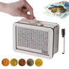 A white wooden money saving box with a grid tracker is shown next to gold coins and paper currency.