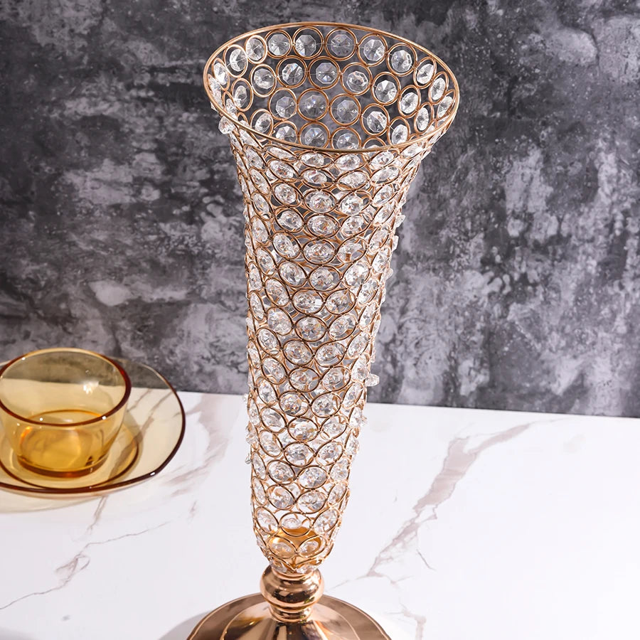 A tall, ornate crystal gold flower vase with a textured surface sits on a white marble surface.