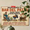 A rustic wooden sign welcomes guests to a bar patio, featuring text about good friends and music.