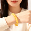 A close-up of a woman's wrist wearing a yellow citrine crystal beaded bracelet.