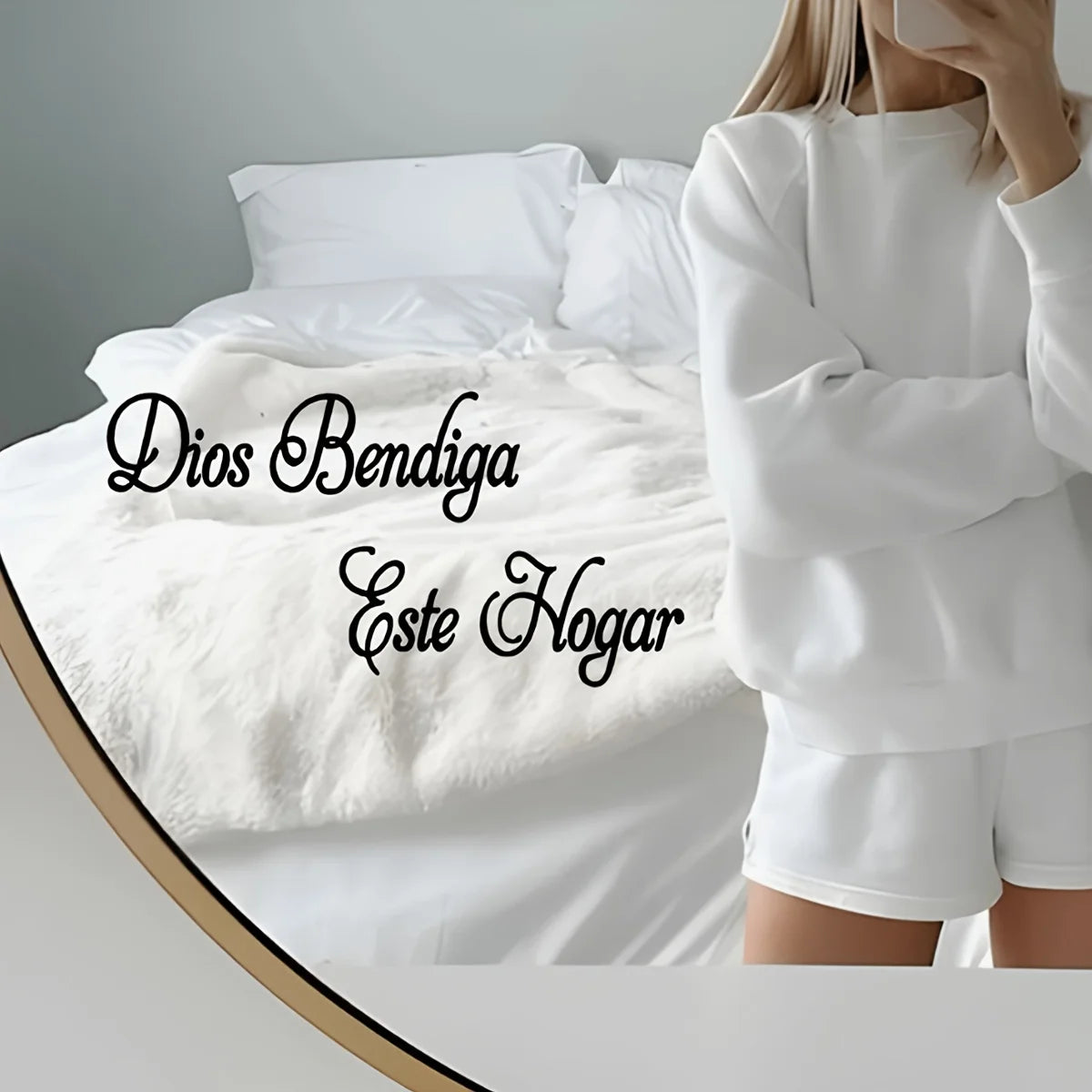 Eine Person in einem weißen Langarmtop steht neben einem Bett mit weißer Bettwäsche und dem Text "Dios Bendiga Este Hogar"