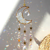 A golden crescent moon dreamcatcher hangs, featuring clear crystals and gold stars, catching light.