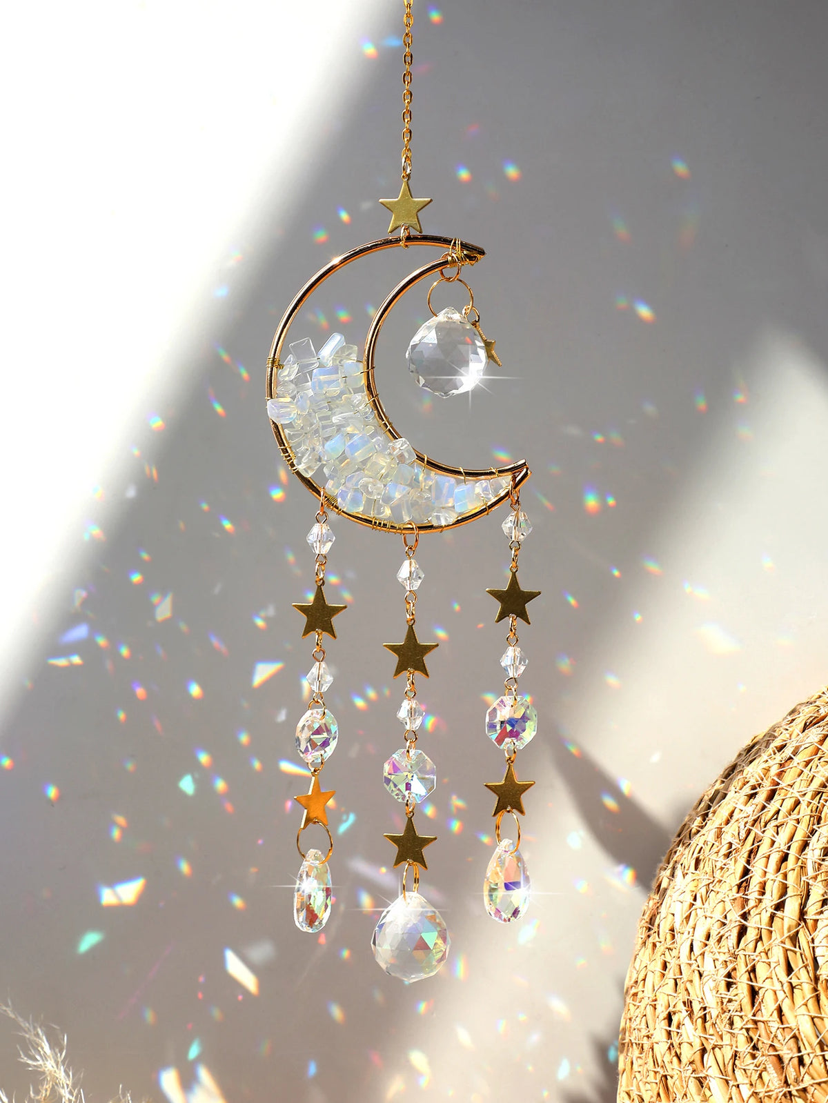 A golden crescent moon dreamcatcher hangs, featuring clear crystals and gold stars, catching light.