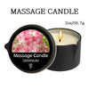 A black jar of Geranium massage candle with a lit wick and pink floral wax.