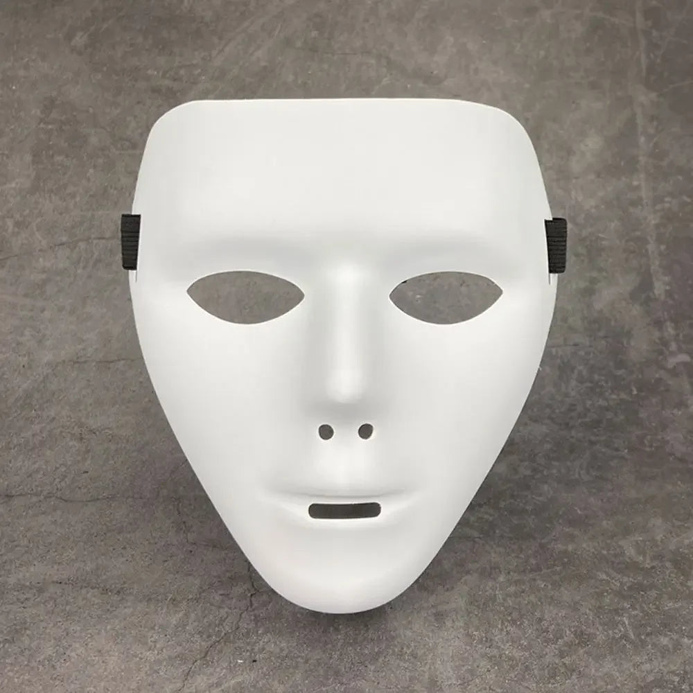 A white, smooth masquerade mask with a stylized face and black ear loops is displayed on a gray surface.