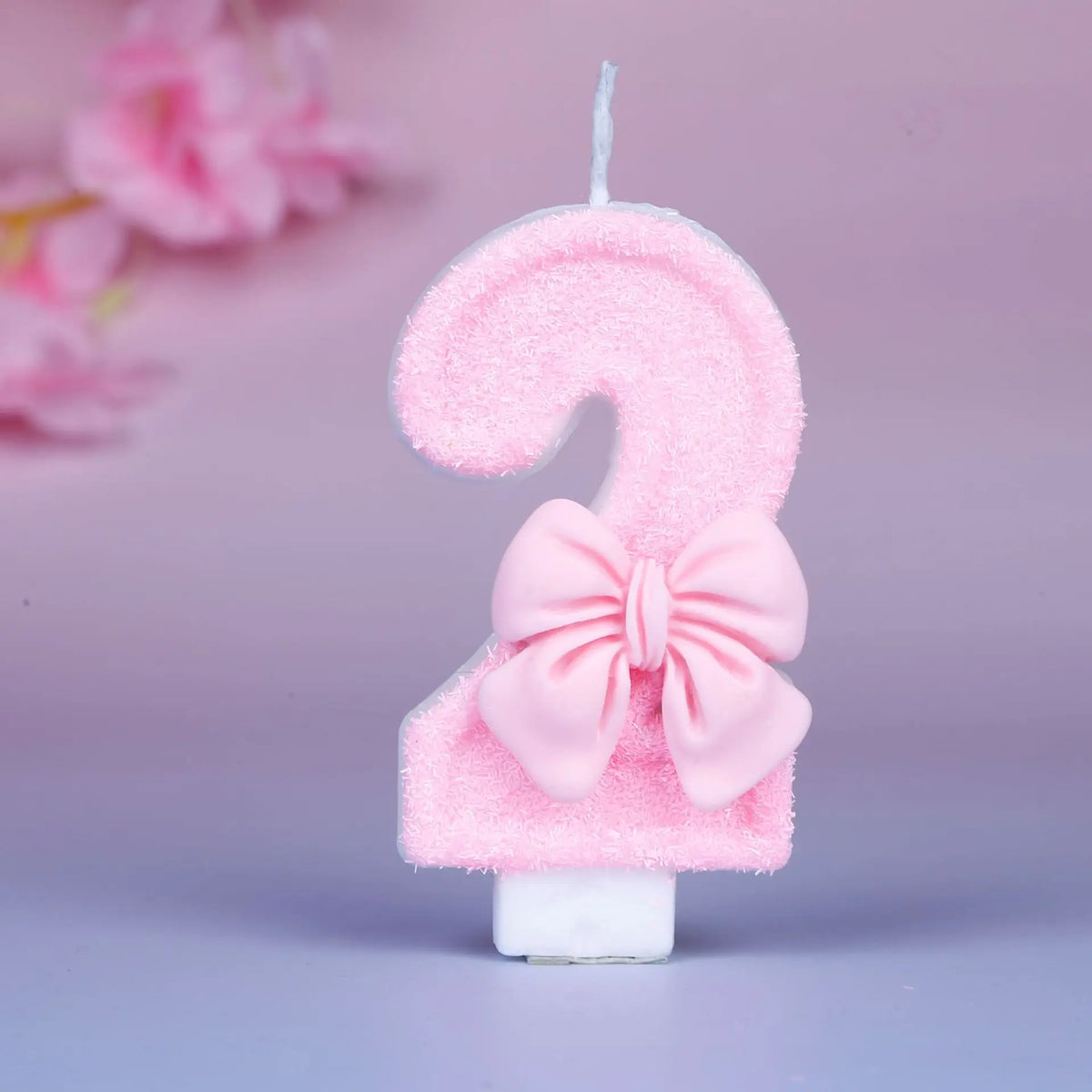 Glittery pink number 3 birthday candle with a decorative pink bow