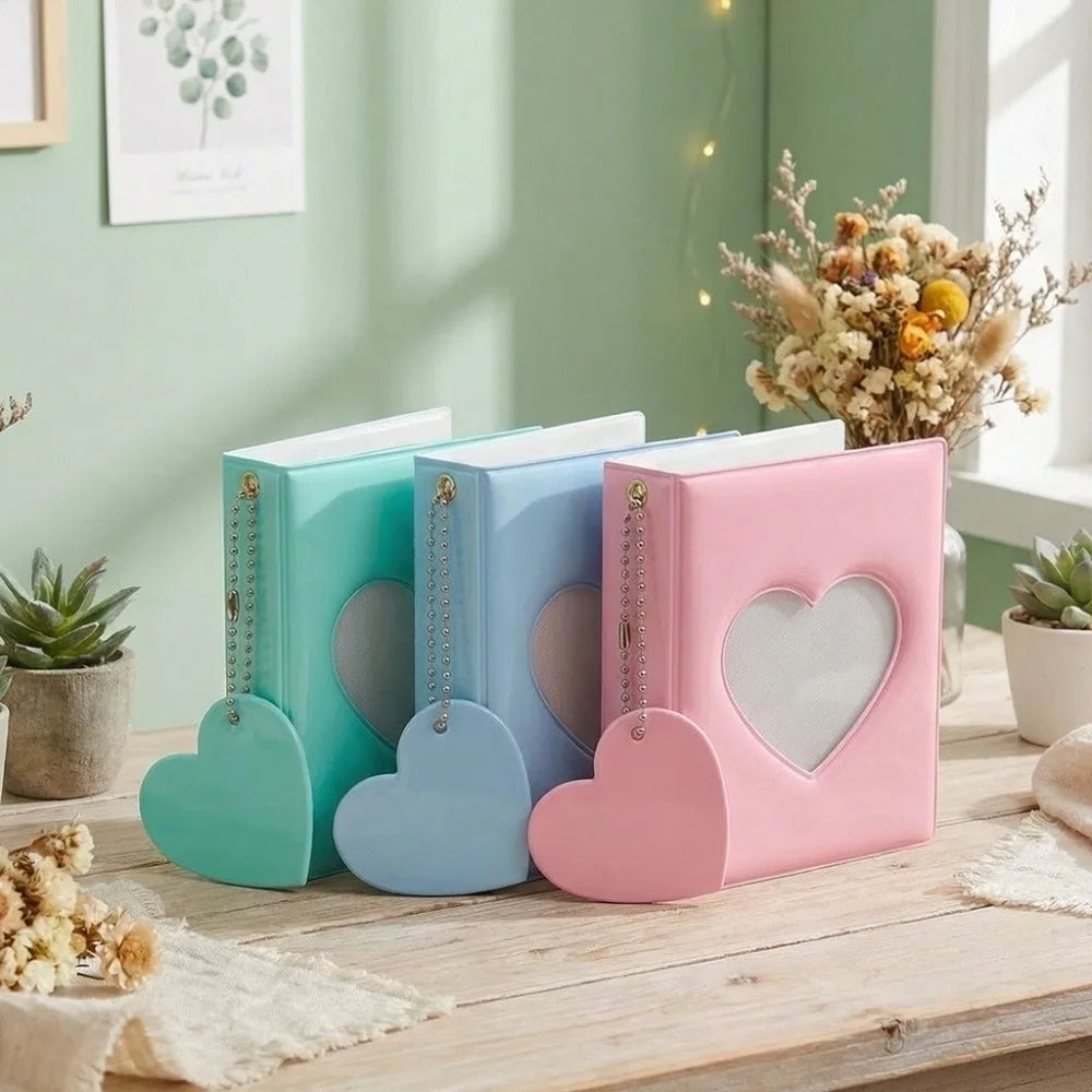 A pink and blue love heart photo album with four pockets resting on a wooden table.