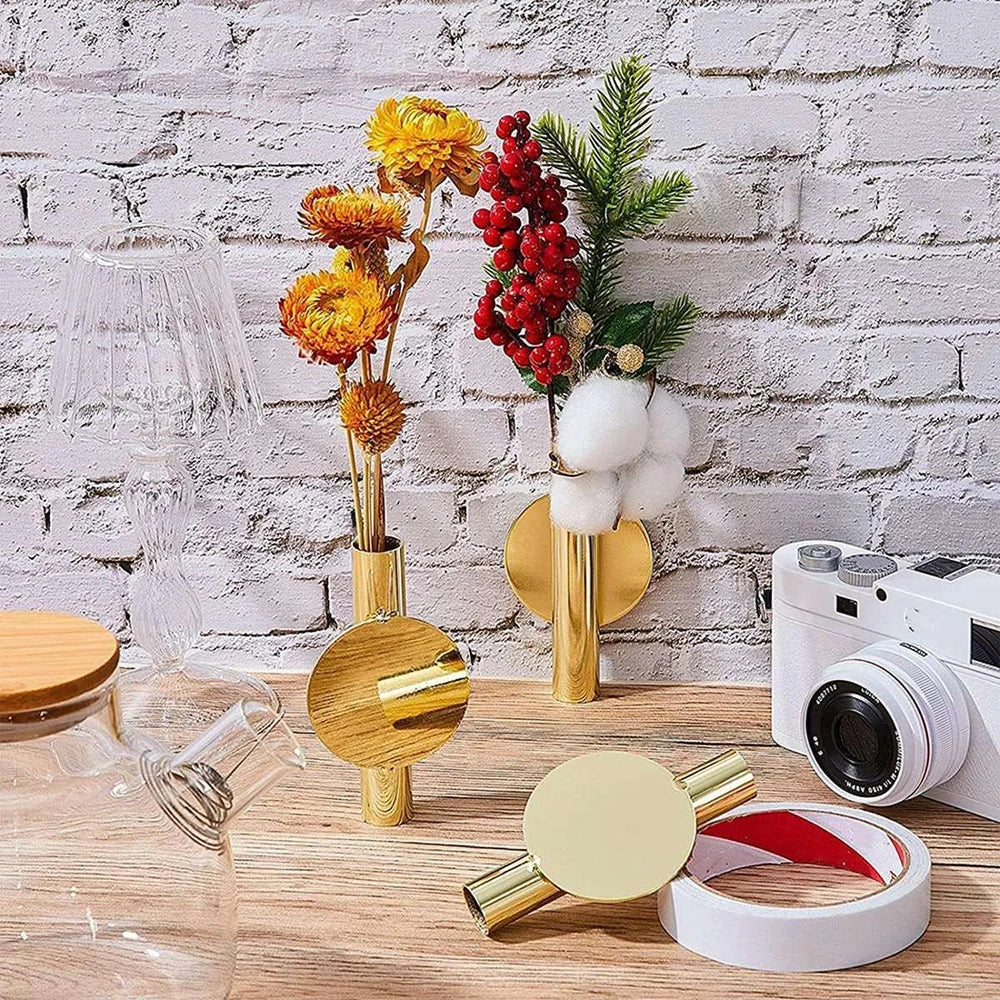 A minimalist wall-mounted metal flower vase with dried yellow flowers and red berries against a white brick background.