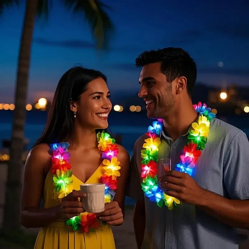A smiling couple holds glow-in-the-dark LED Hawaiian lei necklaces at twilight by the water.