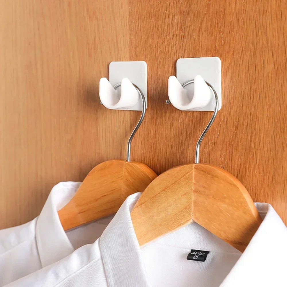 Two white adjustable self-adhesive curtain rod brackets mounted on a wooden wall above a white shirt.