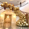 A golden metallic balloon garland decorates a staircase railing in an indoor setting.