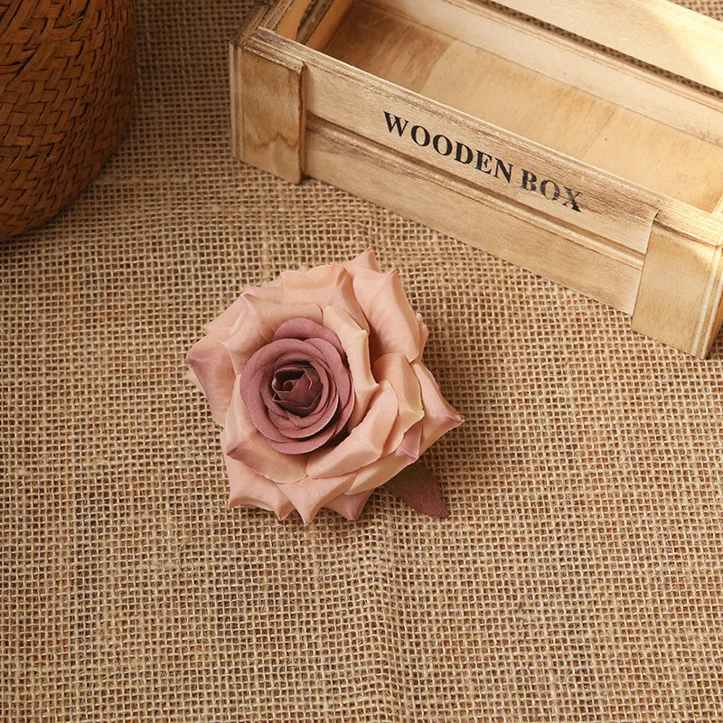 A pink rose flower rests on burlap fabric next to a wooden box labeled Wooden Box.