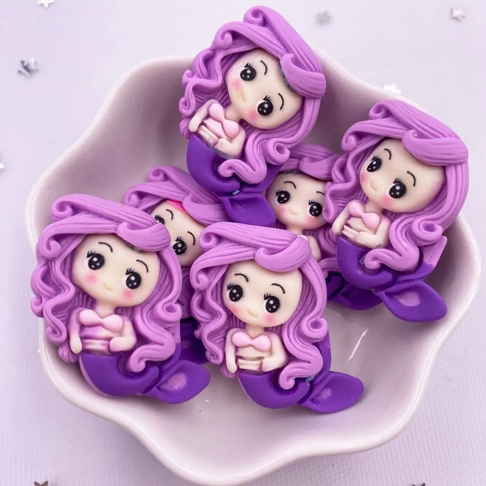 A collection of purple resin mermaid princess figurines with long flowing hair and delicate hands displayed in a pink dish.