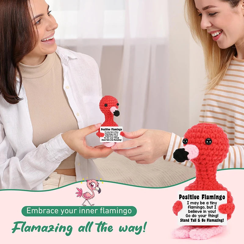 Eine Frau hält eine rote Flamingo-Häkelpuppe, die positive Gefühle und emotionale Unterstützung demonstriert.