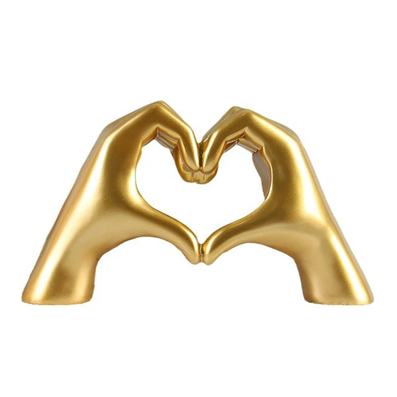 A golden heart-shaped resin hand sculpture designed for desk or shelf decor.