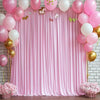 A pink satin backdrop curtain decorated with balloons and gold accents for parties and photography.