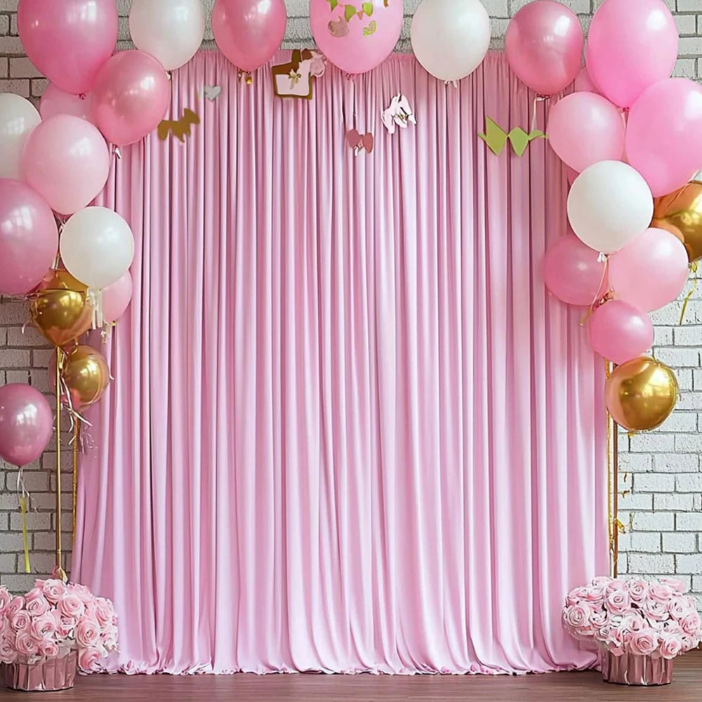 A pink satin backdrop curtain decorated with balloons and gold accents for parties and photography.