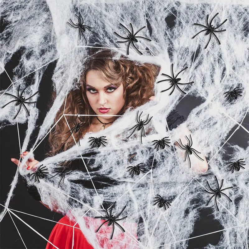A woman is surrounded by a large white spider web with numerous black plastic spiders for Halloween decor.