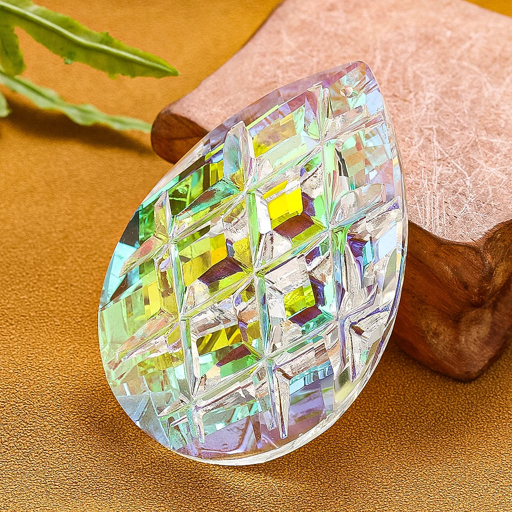 A faceted crystal prism with green and yellow hues rests on a piece of natural fabric.