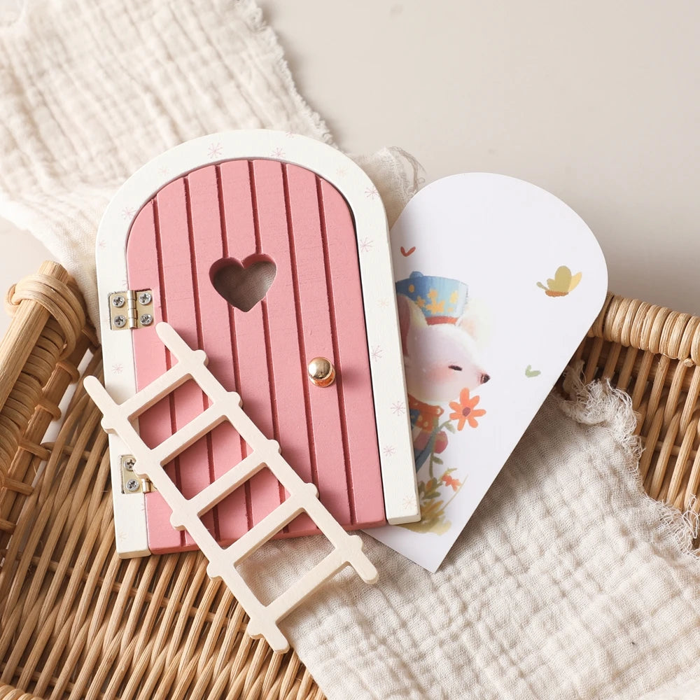 A pink wooden fairy elf door miniature decoration with a heart cutout and a small tooth box placed on a woven basket.