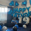Blue and silver foil letter balloons spelling HAPPY BIRTHDAY decorating a party backdrop