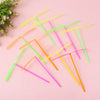 A collection of colorful bamboo dragonfly flying propeller toys arranged diagonally on a pink background.