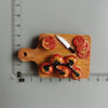 A wooden cutting board displays sliced tomatoes, a knife, and a drizzle of black sauce.
