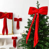 A green Christmas tree decorated with red velvet bows and ornaments.