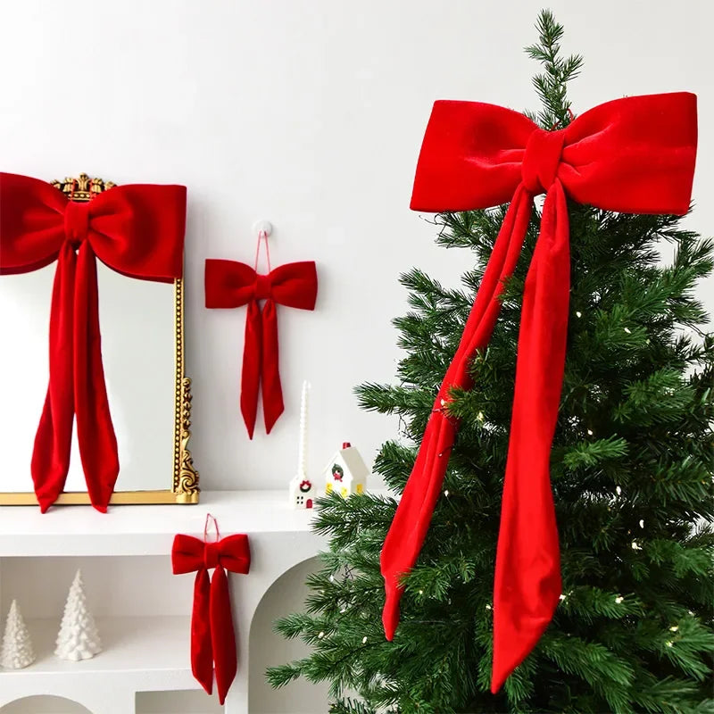 A green Christmas tree decorated with red velvet bows and ornaments.