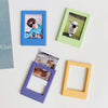 Four magnetic photo frames in blue, green, purple, and yellow displaying different images.