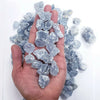 A hand holds a cluster of light blue translucent raw crystal stones for chakra balancing and home decor