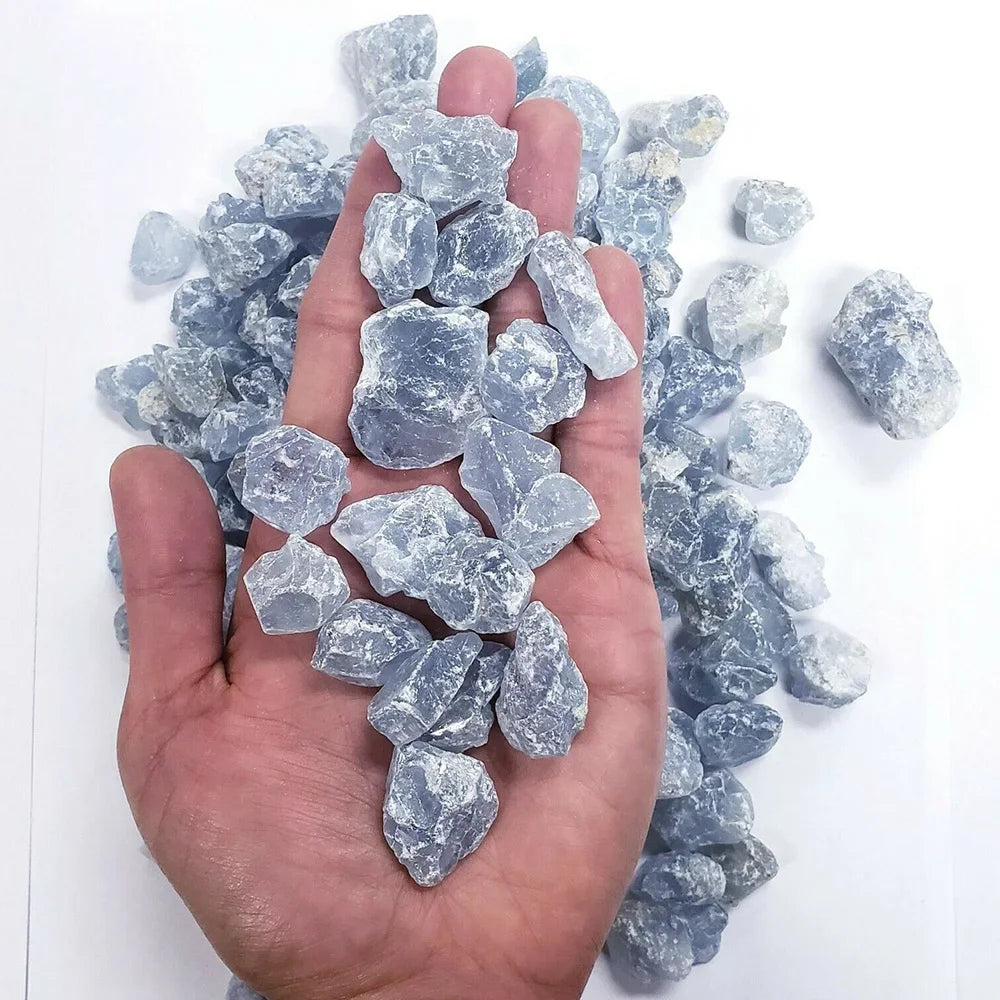 A hand holds a cluster of light blue translucent raw crystal stones for chakra balancing and home decor