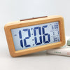 A light wood digital alarm clock displaying 12:06 AM, with features for time, date, and temperature.