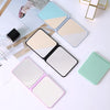 A collection of compact foldable makeup mirrors in various pastel colors and finishes arranged on a white surface.