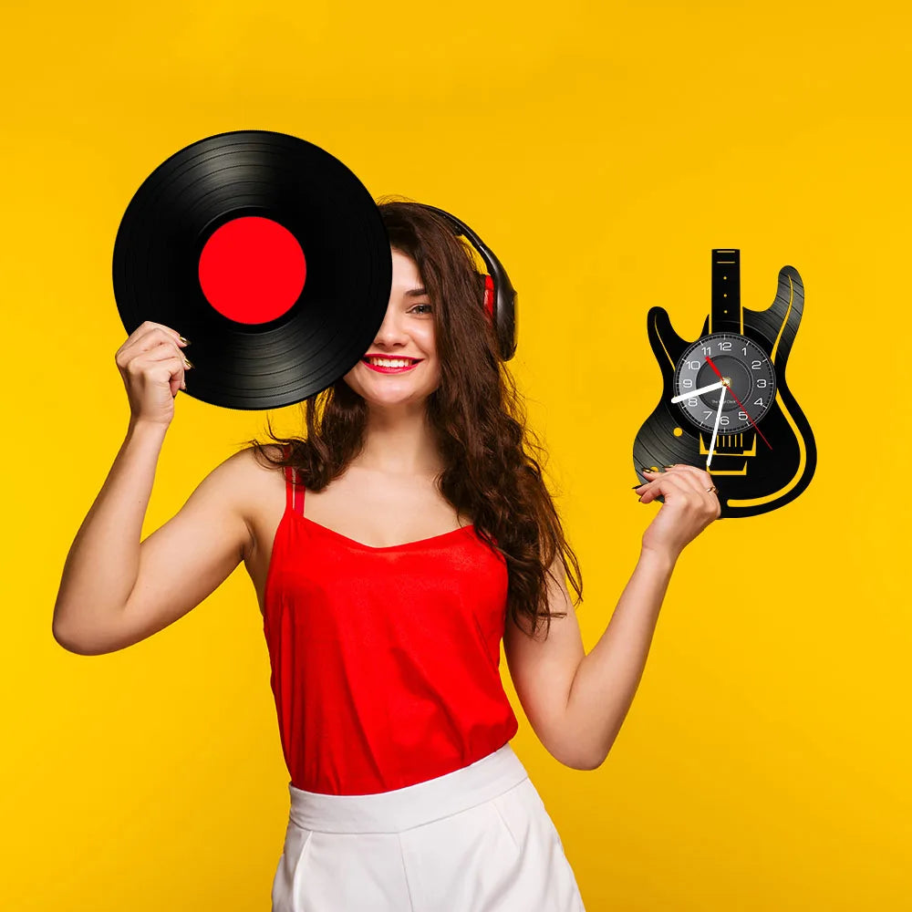 A smiling woman holds a black vinyl record and a black electric guitar against a yellow background.