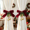 Festive Christmas curtain tie-backs with red bows and pinecones draped in a light fabric.