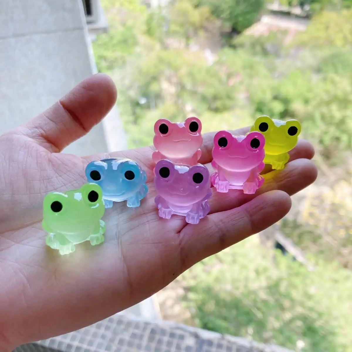 A hand holds several glow-in-the-dark fruit turtle resin charms in various colors like pink, blue, green, and yellow.