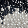 A close-up of black and white heart-shaped acrylic beads scattered on a white surface.