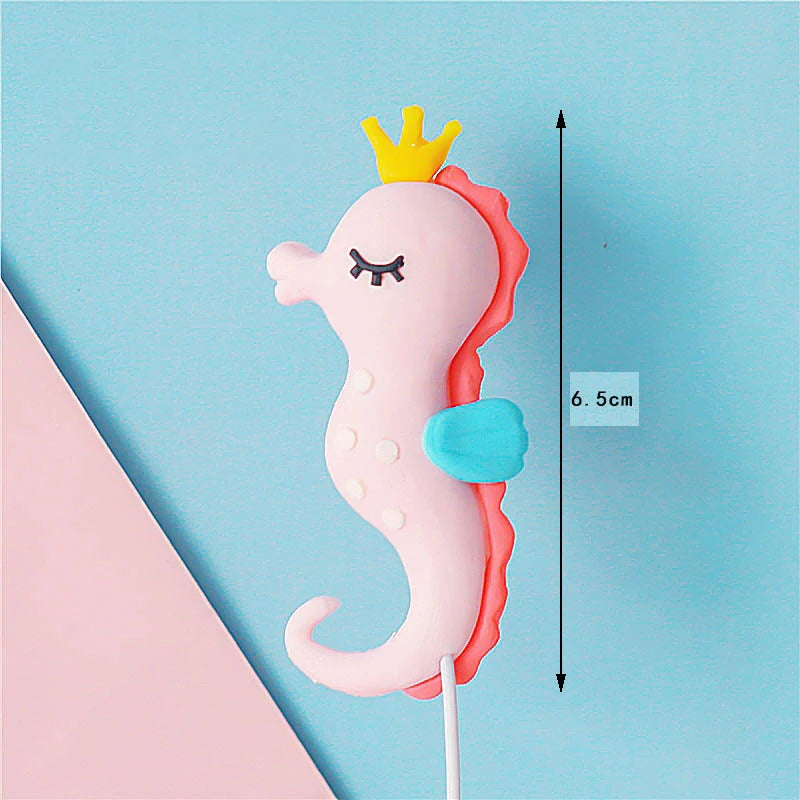 A pink and orange ocean animal cake topper featuring a crab with a crown, set against a light blue background.