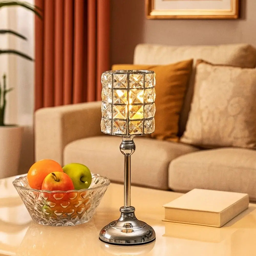Un portavelas de cristal plateado sobre una mesa junto a un tazón de fruta fresca en una acogedora sala de estar.