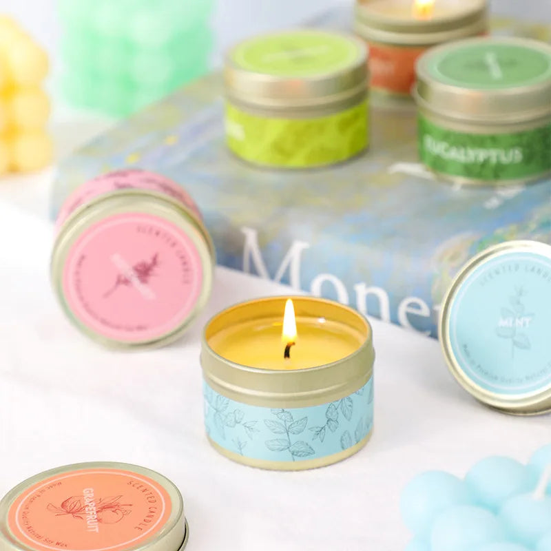 A collection of natural soy wax travel candles in various colors and scents displayed on a white surface.