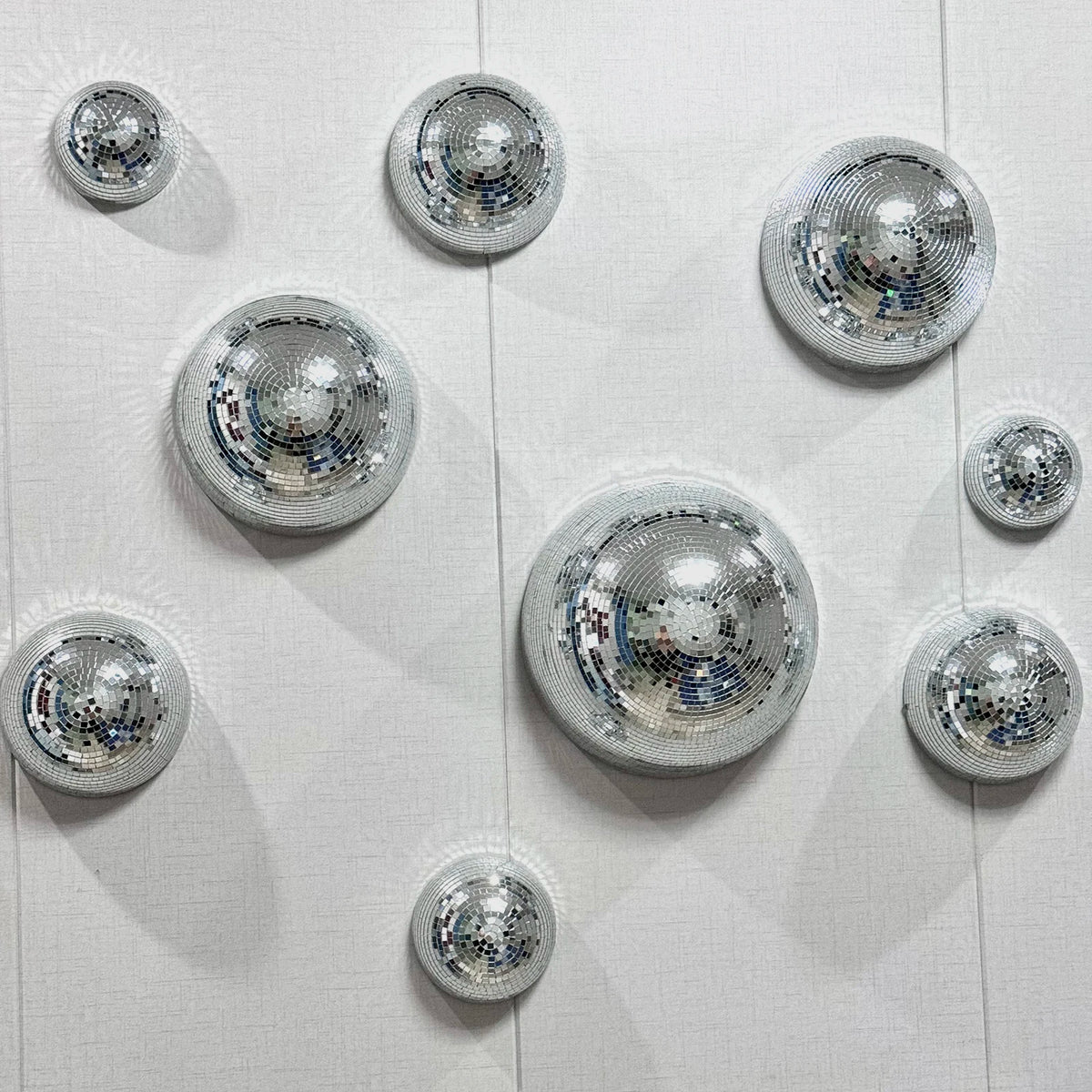 A collection of silver disco balls mounted on a white wall.