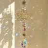 A delicate gold lotus flower crystal glass suncatcher with prism beads and a star charm hanging in sunlight.