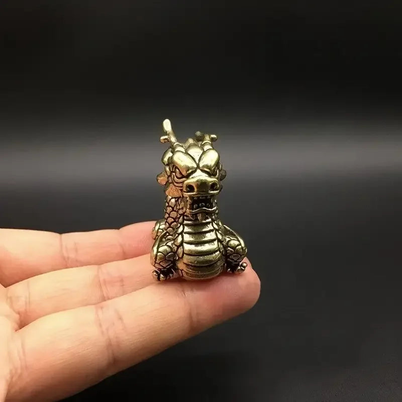 Handcrafted brass Chinese dragon statue held in a person's hand.