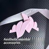 Pink 3D printed monitor wing decorations with a white ribbon on a black textured background
