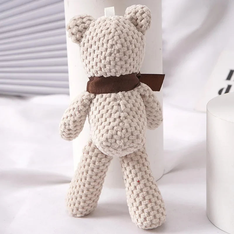 A light beige crocheted stuffed bear with brown accents standing upright.