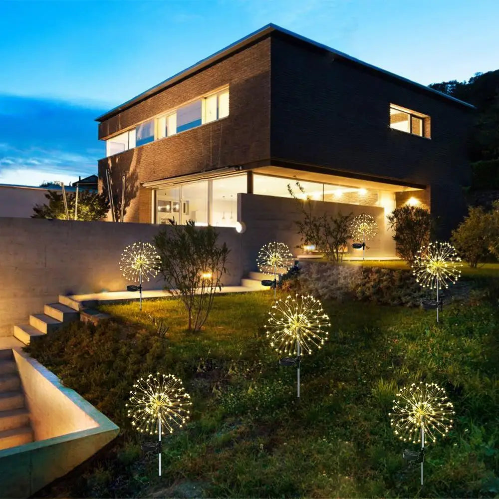 Maison moderne éclairée par une lumière chaude, ornée de nombreux feux d'artifice LED solaires décorant le paysage du jardin.