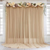 A beige chiffon backdrop curtain decorated with floral greenery and light flowers for wedding or event decor.
