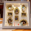 Weiße dekorative Box mit mehreren verzierten, goldgerahmten Silhouetten-Souvenirs.