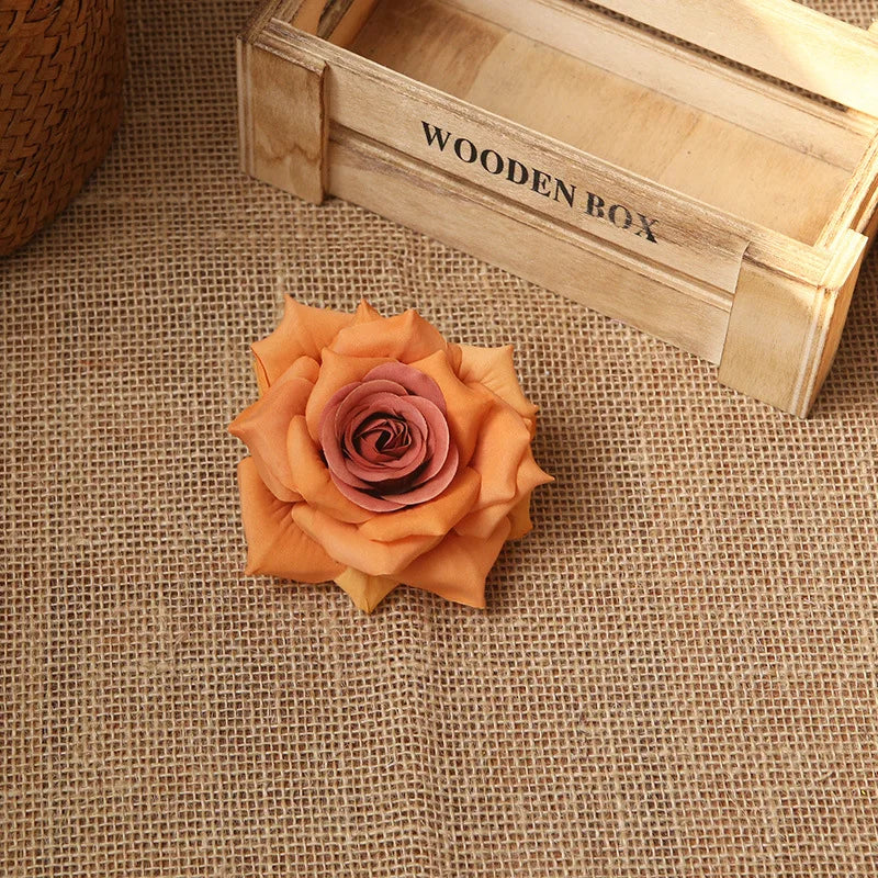 An orange rose flower rests on a burlap surface next to a wooden box labeled Wooden Box.